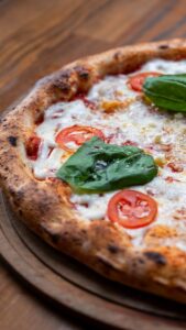 Delicious Margherita pizza with tomatoes and basil leaves on a rustic wooden table.